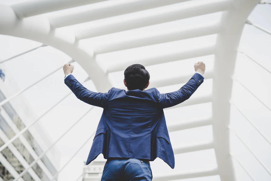 successfully-young-businessman-keeping-arms-raised-expressing-positivity-while-standing-outdoors_1150-3054